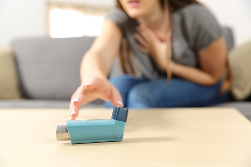woman reaches for asthma inhaler