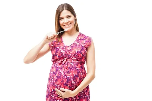 pregnant woman brushes her teeth